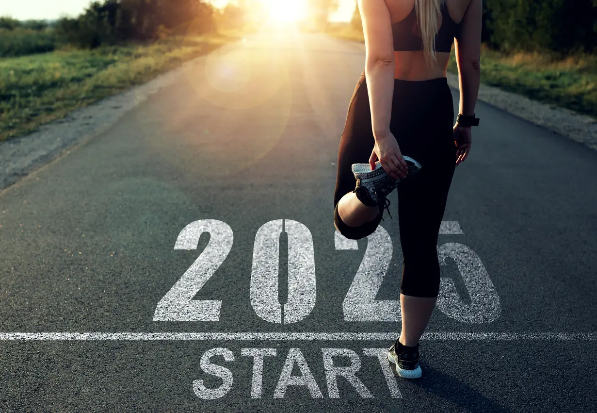 2025 fitness goals examples: A woman stretching on an open road with '2024 Start' written on the pavement, symbolizing the beginning of a fitness journey