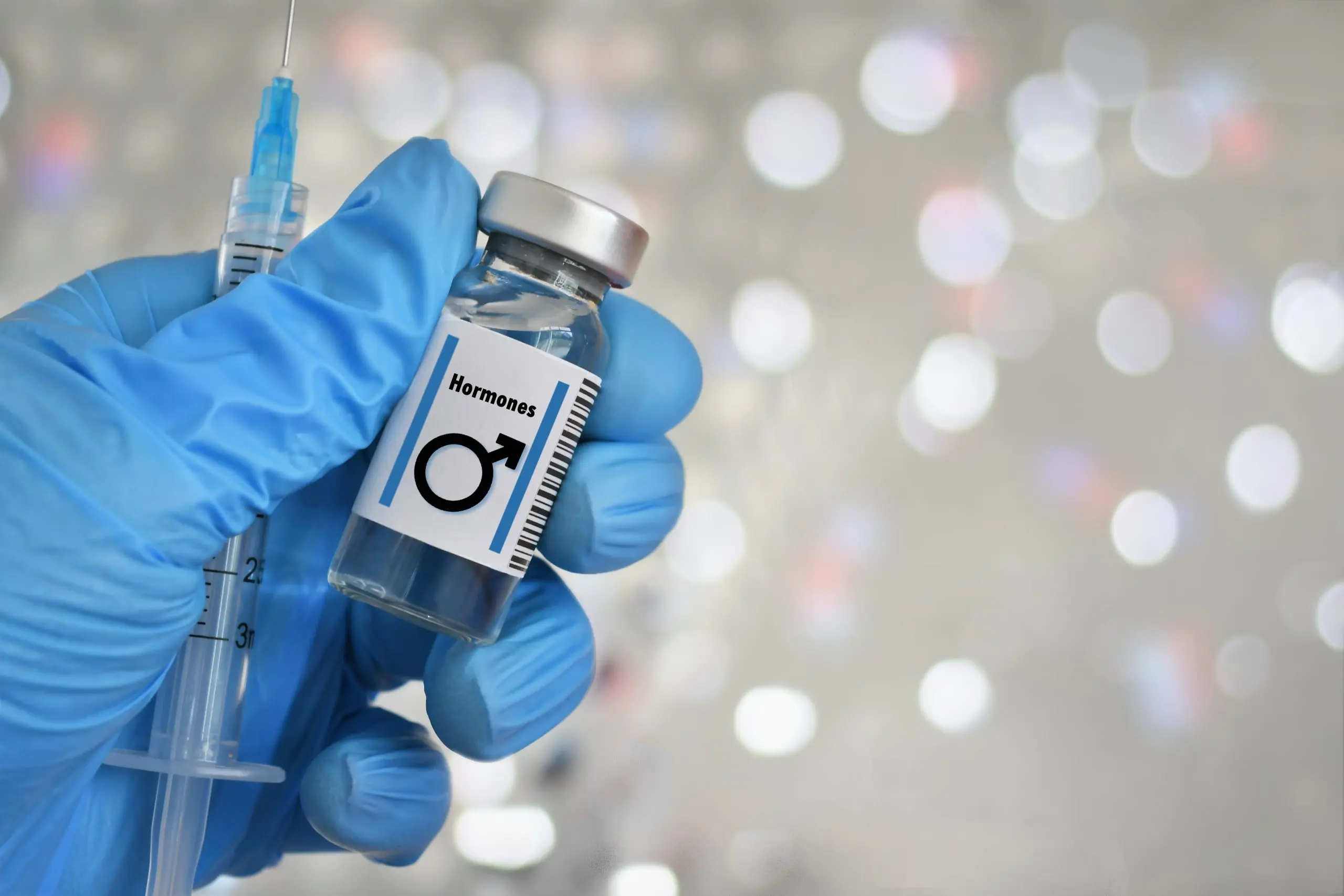 A hormone vial labeled 'TRT' held by a gloved hand with a syringe, illustrating the topic 'how expensive is TRT' and its associated medical costs.